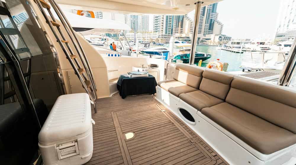 yacht aft deck with sofa seating, staircase to upperdeck, docked at dubai marina